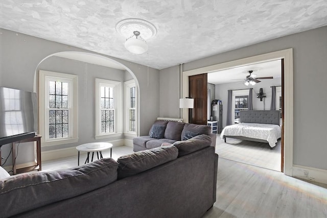 living room featuring light wood-style floors, a textured ceiling, and baseboards