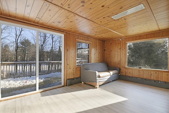 unfurnished sunroom featuring wooden ceiling, a skylight, and a baseboard heating unit