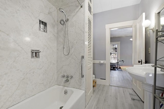 bathroom with toilet, wood finished floors, and shower / bathing tub combination