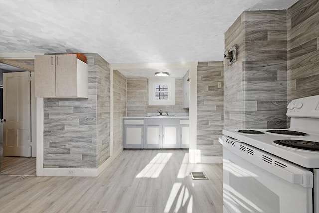 kitchen featuring white range with electric stovetop, visible vents, tile walls, light countertops, and a sink