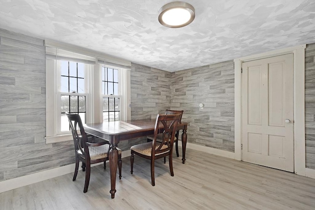 dining area with a textured ceiling, baseboards, and light wood-style floors