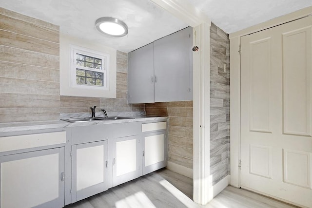 kitchen featuring light wood finished floors, light countertops, and a sink