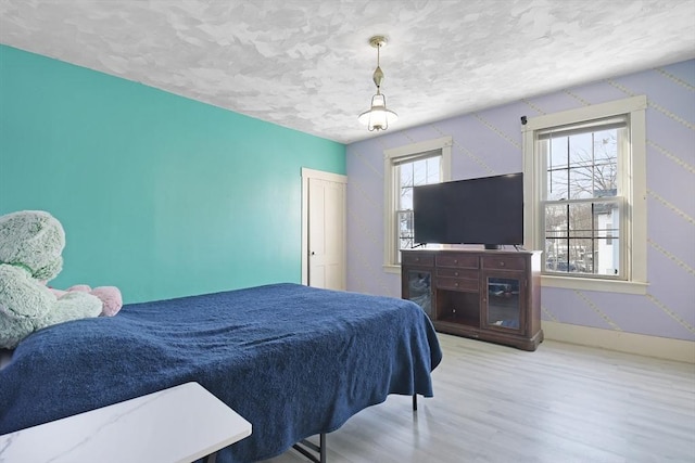 bedroom with a textured ceiling, baseboards, and wood finished floors