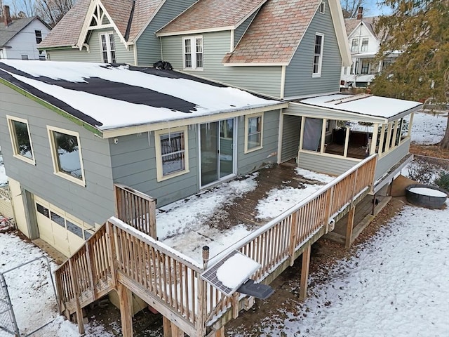 snow covered rear of property featuring a sunroom and stairs