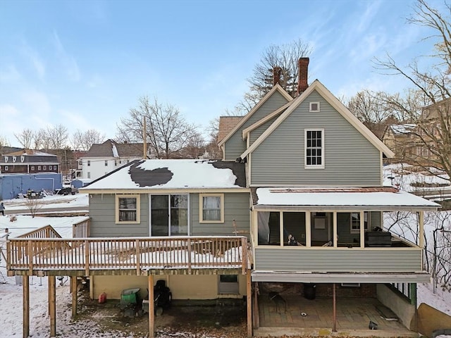 snow covered property featuring a deck and a sunroom