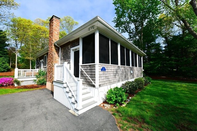 173 Standish Rd, Bourne, MA 02562 - view of side of home featuring a chimney, a sunroom, a yard, and a patio