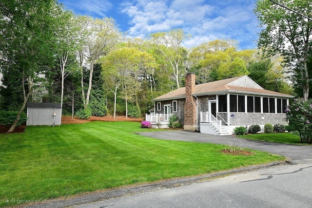 173 Standish Rd, Bourne, MA 02562 - view of front facade featuring a sunroom, a chimney, a front lawn, and view of wooded area