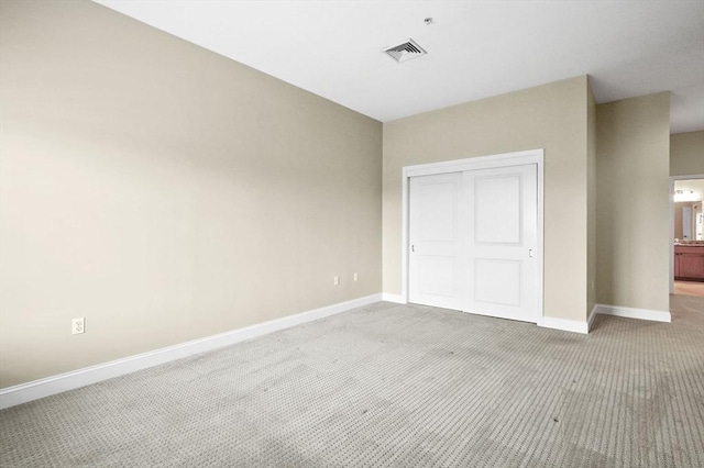unfurnished bedroom with light colored carpet, baseboards, and a closet