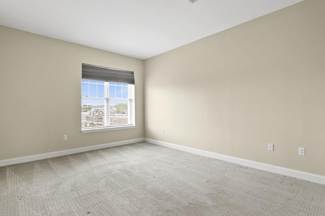 empty room featuring baseboards and light colored carpet
