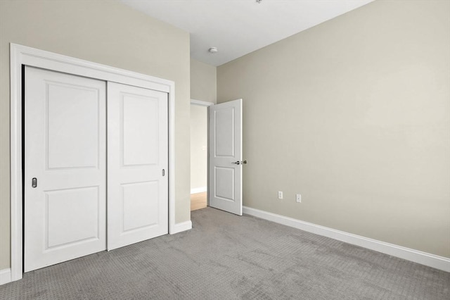 unfurnished bedroom featuring carpet flooring, a closet, and baseboards