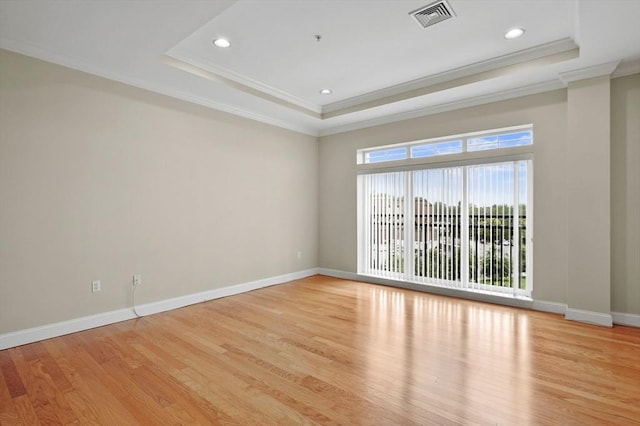 spare room with crown molding, a raised ceiling, light wood-type flooring, baseboards, and recessed lighting