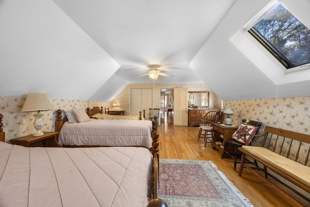 bedroom with hardwood / wood-style flooring, ceiling fan, and vaulted ceiling with skylight