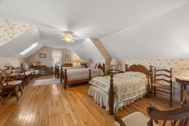 bedroom featuring ceiling fan, light wood-type flooring, and lofted ceiling with skylight