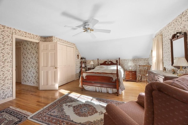 bedroom with ceiling fan, vaulted ceiling, light wood-type flooring, and a closet