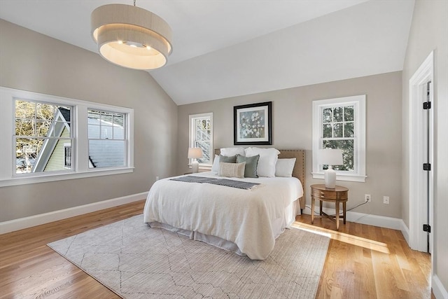 bedroom with vaulted ceiling, light hardwood / wood-style floors, and multiple windows