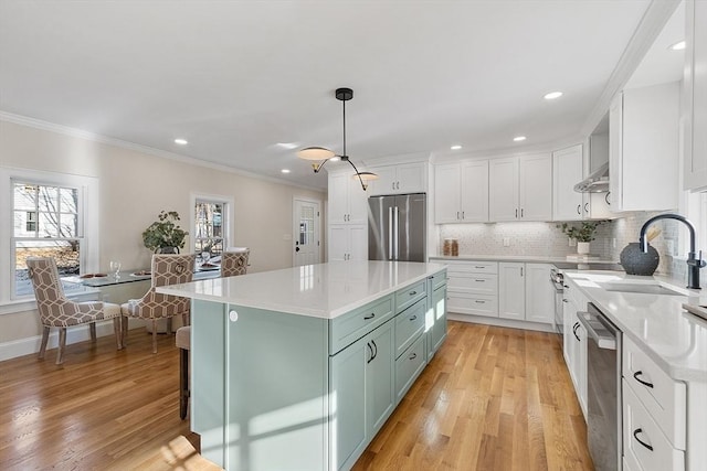 kitchen featuring appliances with stainless steel finishes, white cabinets, decorative light fixtures, and a center island