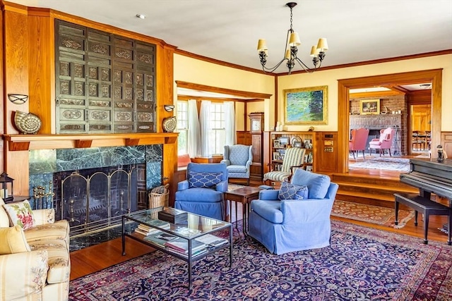 living room with a premium fireplace, an inviting chandelier, crown molding, and wood finished floors
