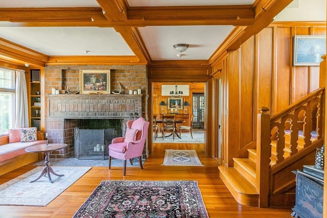 living area featuring wood walls, wood finished floors, a brick fireplace, and stairs