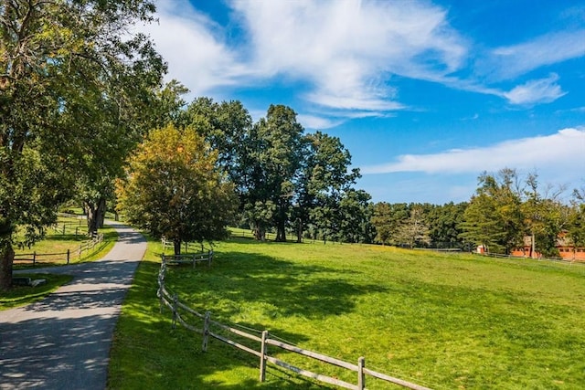 surrounding community with a rural view, fence, and a lawn