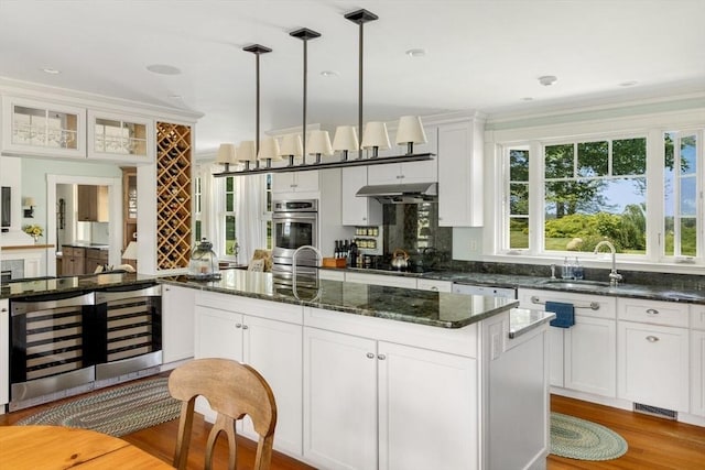 kitchen featuring beverage cooler, under cabinet range hood, a sink, white cabinetry, and black electric cooktop