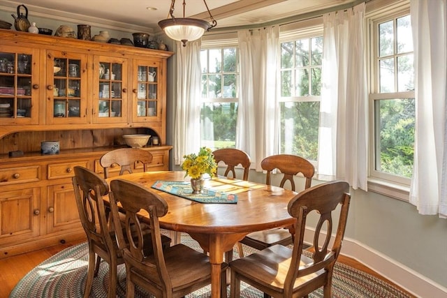 dining room with crown molding, light wood-style flooring, baseboards, and a healthy amount of sunlight