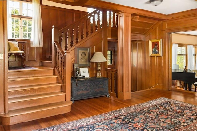 stairway featuring wooden walls, a healthy amount of sunlight, and wood finished floors