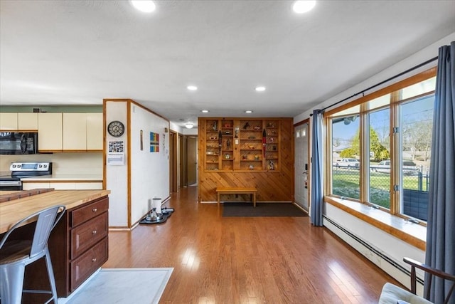 interior space featuring built in shelves, a baseboard radiator, recessed lighting, wood finished floors, and wood walls