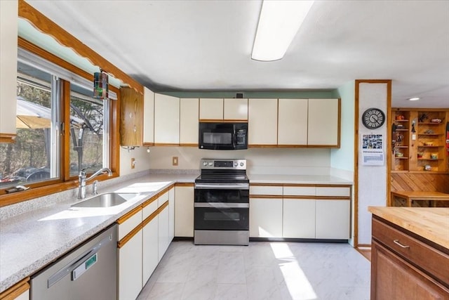 kitchen featuring a sink, light countertops, appliances with stainless steel finishes, and marble finish floor