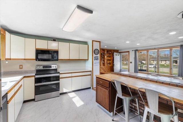 kitchen with cream cabinets, appliances with stainless steel finishes, marble finish floor, and recessed lighting