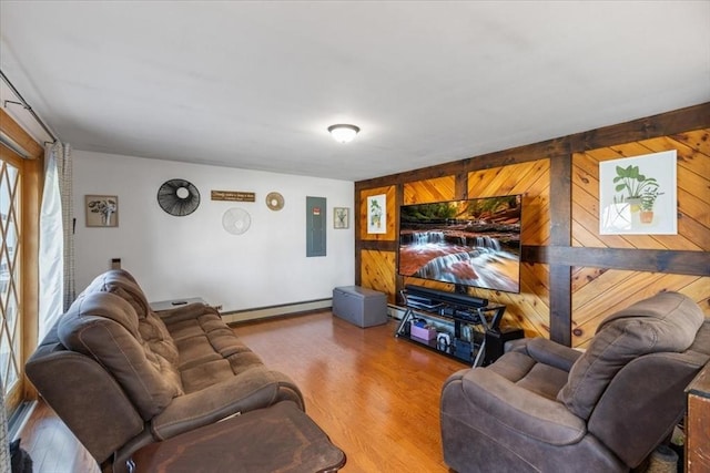 living area with wood walls, a baseboard radiator, wood finished floors, and electric panel