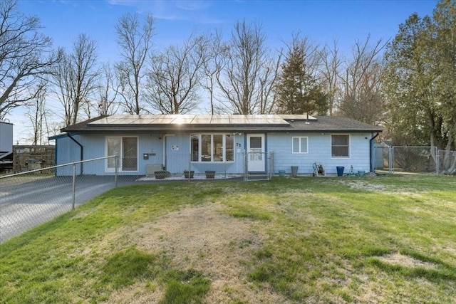 ranch-style home with fence, driveway, a front lawn, a gate, and roof mounted solar panels