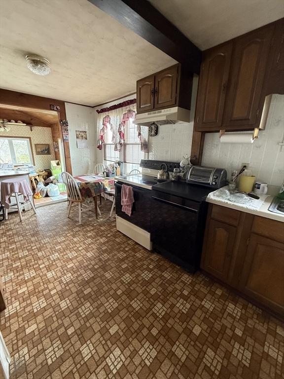 kitchen with electric range, brick patterned floor, washer / clothes dryer, light countertops, and under cabinet range hood