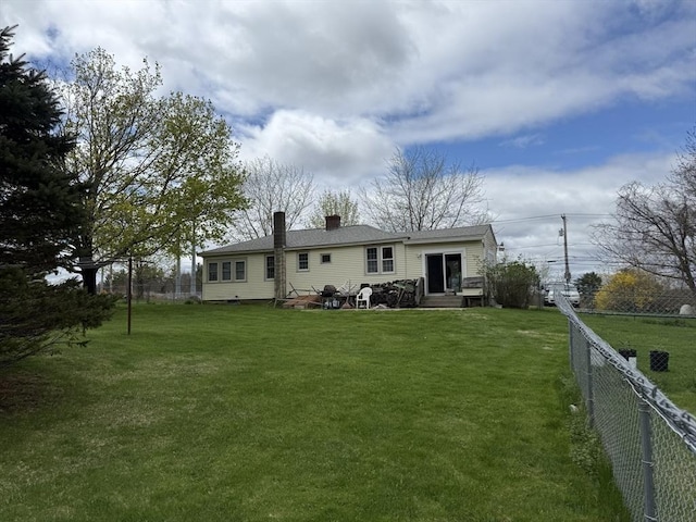 rear view of property with fence, a chimney, a yard, and entry steps