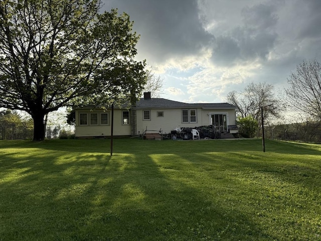rear view of house with a chimney and a yard