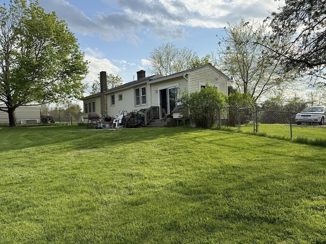 back of house with fence, a chimney, and a yard