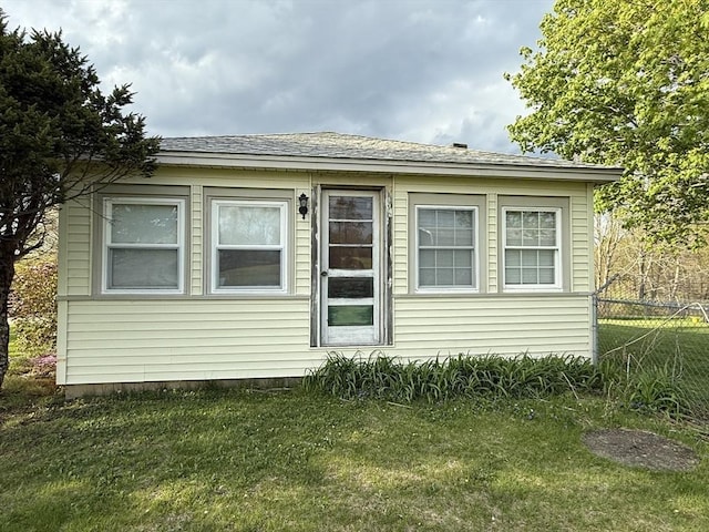 rear view of property featuring fence and a yard