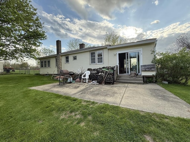 rear view of property with a lawn, a chimney, and a patio area