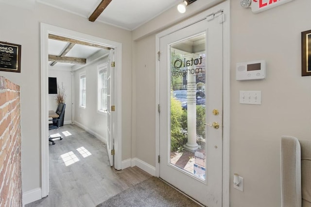doorway to outside featuring beamed ceiling, baseboards, and wood finished floors