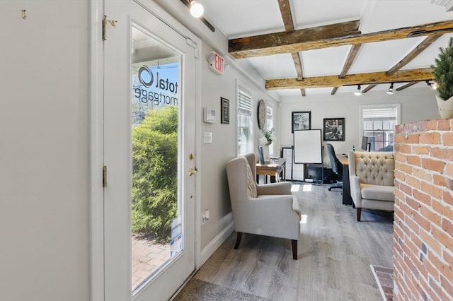 interior space with light wood finished floors, baseboards, and beam ceiling