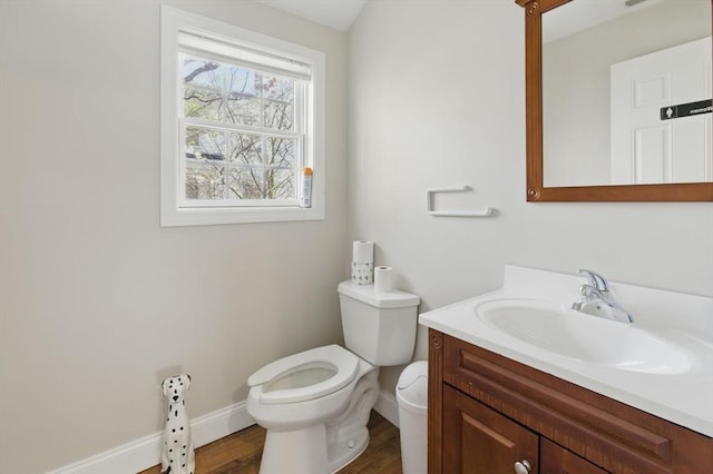 half bath featuring vanity, toilet, baseboards, and wood finished floors