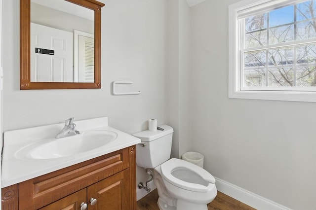 half bath featuring toilet, baseboards, vanity, and wood finished floors