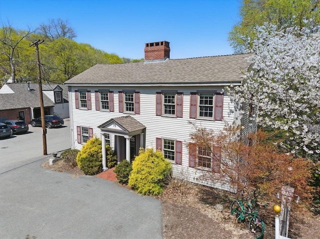 colonial house featuring a shingled roof and a chimney