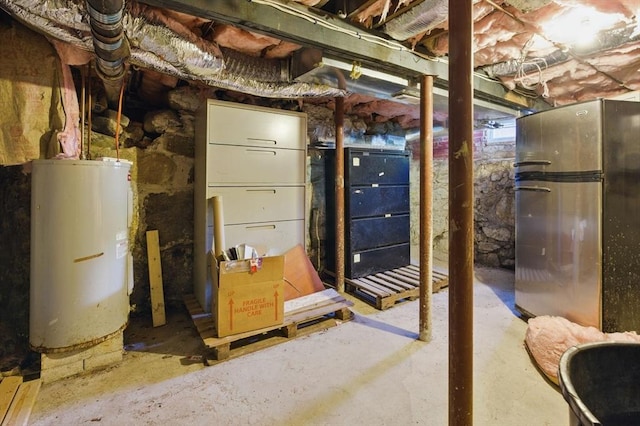 unfinished below grade area featuring gas water heater and freestanding refrigerator