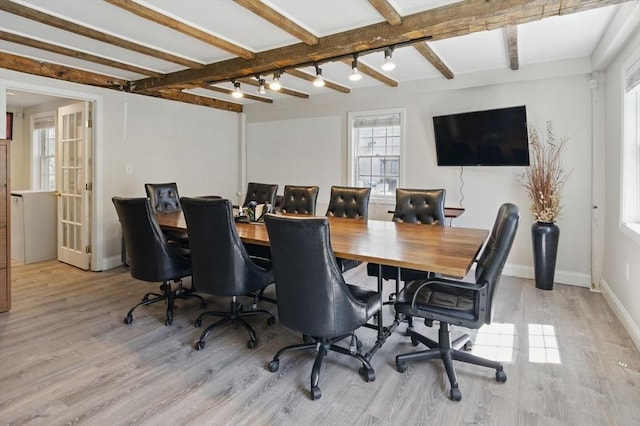 office space with light wood-style floors, baseboards, and beamed ceiling
