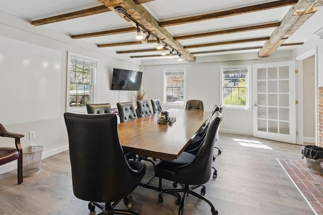 dining room with light wood finished floors, baseboards, and beam ceiling