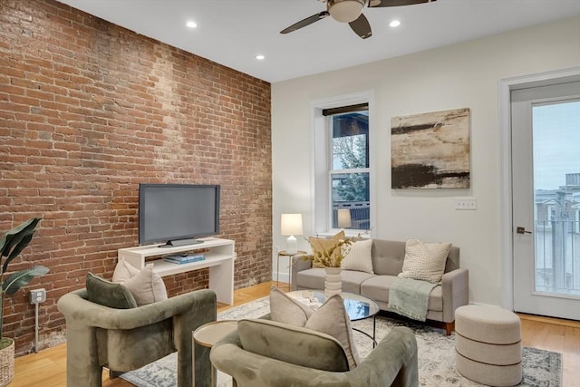 living room featuring plenty of natural light, brick wall, and light wood-type flooring