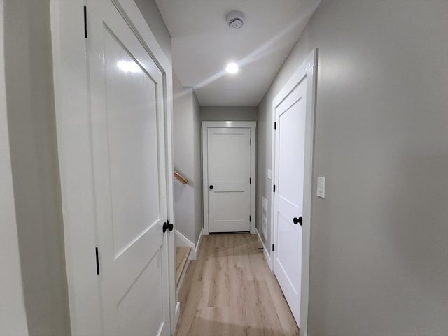 hall featuring light wood-style flooring and baseboards