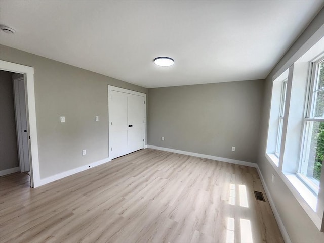 spare room featuring healthy amount of natural light, light wood finished floors, and baseboards