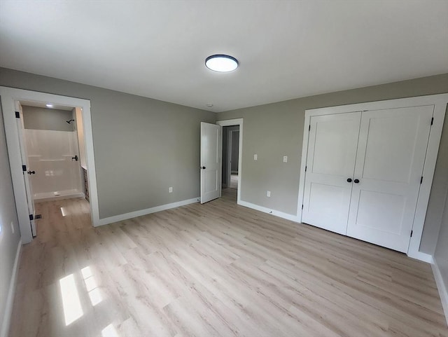 unfurnished bedroom with light wood finished floors, baseboards, a closet, and ensuite bathroom