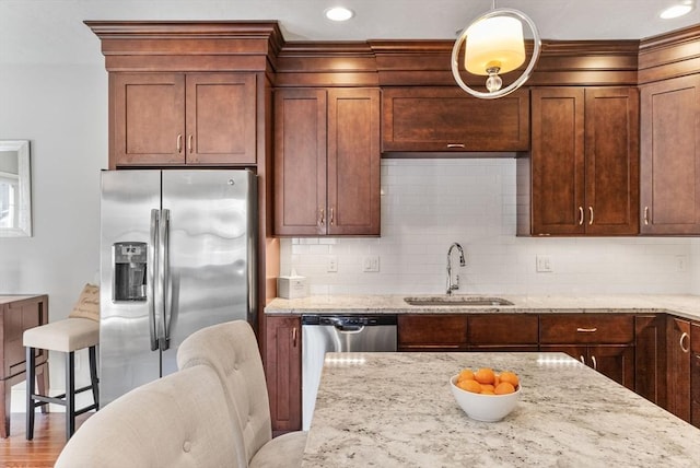 kitchen with stainless steel appliances, tasteful backsplash, a sink, and light stone countertops